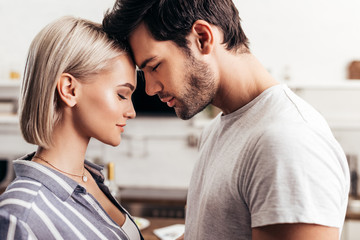 selective focus of handsome boyfriend and attractive girlfriend standing in kitchen