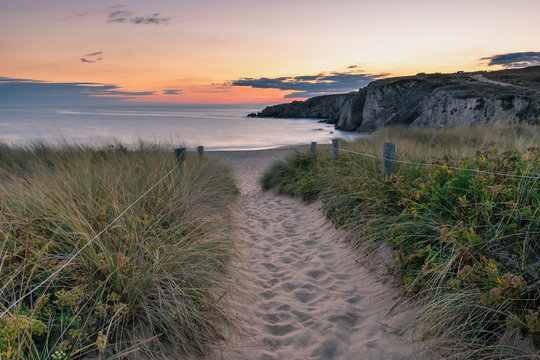 French landscape - Bretagne. A beautiful beach with dunes and  wild cliffs in the background at sunset.
