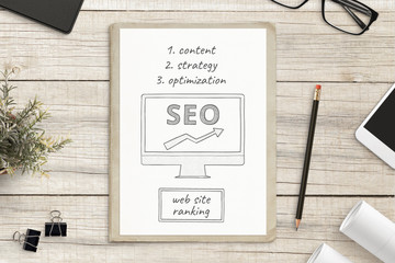 Search engine optimization sketch on white paper surrounded with office supplies. SEO web site concept.