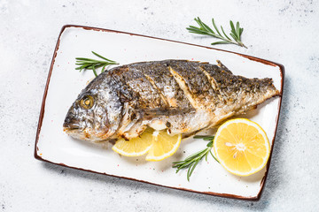 Baked dorado fish with lemon and rosemary top view.