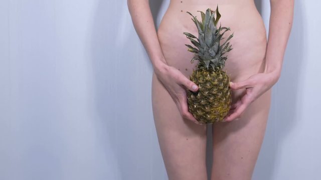 Naked woman's body with pineapple in her hands.