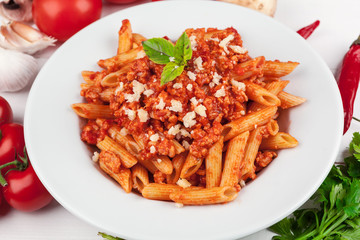 Pasta with meat, tomato sauce and vegetables on the table