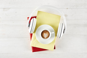 Electronic audiobook vs regular paper book concept. Stack of different color hardcover books with blank colorful covers & white headphones on table. Old versus new. Close up, copy space, background.