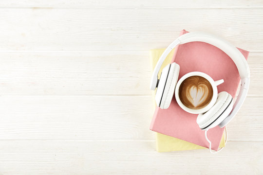 Electronic audiobook vs regular paper book concept. Stack of different color hardcover books with blank colorful covers & white headphones on table. Old versus new. Close up, copy space, background.