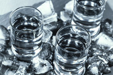 Cold vodka in shot glasses on a black background.