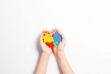 Child hands holding colorful heart on white background. World autism awareness day concept