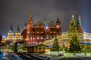 Winter night view of the big Christmas tree and decoration on the Manezhnaya square with the State historical Museum, Iverskaya chapel and Uglovaya Arsenal'naya tower of Kremlin in Moscow, Russia.