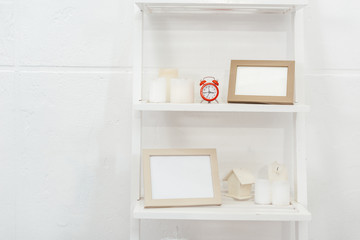 shelves with red clock, wooden frameworks and candles on white background