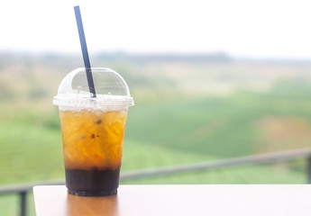 Cup plastic of ice tea on wooden table in the garden