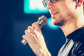 Speaker on the stage: Young Caucasian man is talking into a mirophone