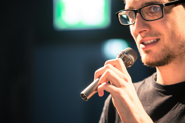 Speaker on the stage: Young Caucasian man is talking into a mirophone