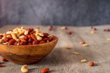 Hazelnuts, cashews, Brazil nuts and almond wooden bowls on a gray background.
