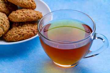 Oatmeal cookies and a cup tea on a blue background. Flour, cereal dessert and hot drink