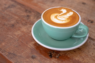 Hot coffee cappuccino latte art on the swan shape on wooden background , vintage style.