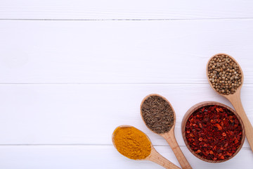 Spices mix on wooden spoons on a white wooden background. Top view