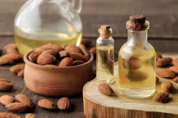 Fototapeta na wymiar natural almond oil in a glass bottle and fresh almond nuts close-up on a brown wooden table.