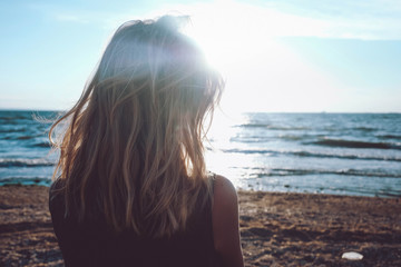 Girl looks on the sea. Dreary blonde girl looks at the sea. Sad for a loved one alone.