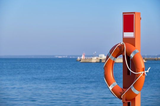 Orange lifebuoy by the sea - Powered by Adobe