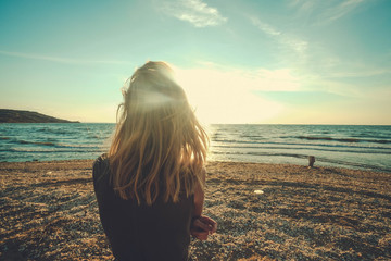 Girl looks on the sea. Dreary blonde girl looks at the sea. Sad for a loved one alone.