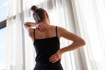 Young woman suffering from neck pain and backache, stretching the muscles at home. back and neck pain woman