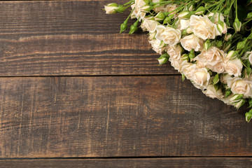 Fototapeta premium Frame of beautiful mini roses on a brown wooden table. beautiful flowers. holidays. top view