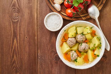 meatballs soup in white plate on old wooden rustic brown table, top view