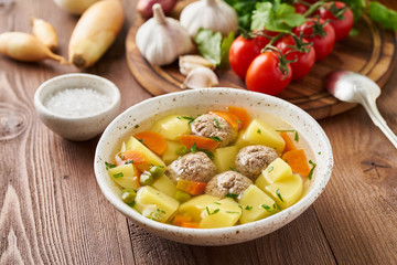 meatballs soup in white plate on old wooden rustic brown table, side view