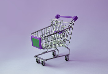 Shopping trolley on soft pink pastel background with copy space. Shopping cart on pink background in minimalism style.