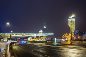 Fototapeta na wymiar Moskvoretskaya embankment near Zaryadye Park with the illuminated floating bridge. Moscow, Russia.