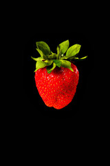Strawberries on a black background with green leaves background close-up