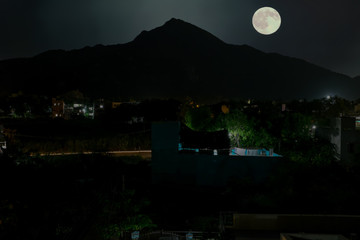 The holy mountain Arunachala with full moon in India at night
