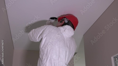Back Of Constructor Man With Helmet Cutting Hole In Ceiling Stock