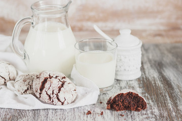 Handmade chocolate cookies, glass and jug with milk, blurred background