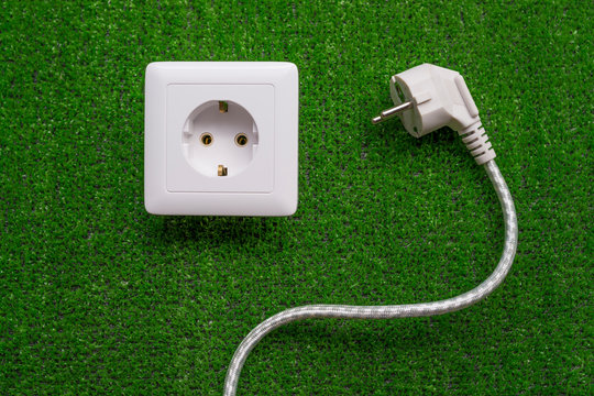 socket on a background of artificial green grass. electricity, appliances.