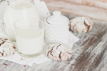 Handmade chocolate cookies, glass and jug with milk, blurred background