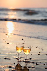 Two wine glasses with white wine standing on beach
