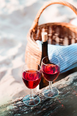 Two wine glasses, wicker basket on beach