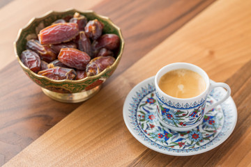 Turkish coffee and dates in cup on brown wooden table