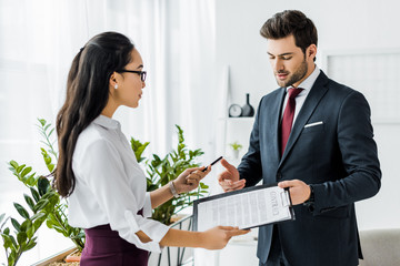 businesspeople in formal wear signing contract in office