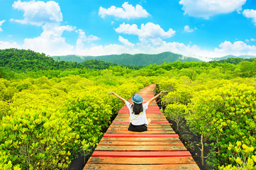 teen girl sit on wooden bridge relaxing with mangrove nature trail against beauty blue sky