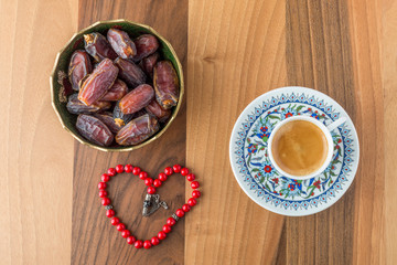 Turkish coffee, dates, and heart shaped rosary on brown table top view
