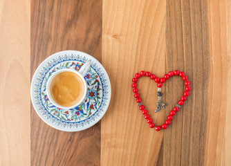 Turkish coffee and heart shaped red rosary on brown table top view