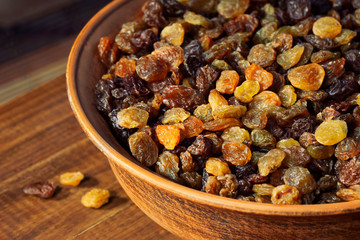 Raisins in a ceramic bowl on a wooden table.  Assortment of Raisins.