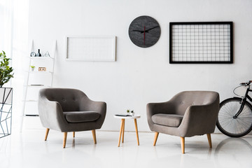 modern interior of white waiting hall with grey armchairs and table