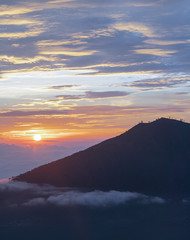 Beautiful and Magnificent early morning Sunrise at Mount Batur, A live volcanic mountain, Blue and Orange glow in the sky with silhouette of mountains and fogs on the bottom of the hills
