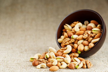 Walnut platter spilled out of the cup on the background of cloth from burlap. Nuts as structure and background, macro.