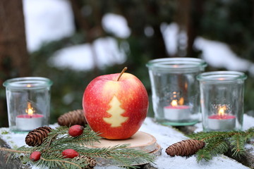 Weihnachtsdekoration mit Apfel und Kerzen im Glas