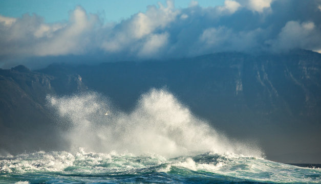 Big waves break on the rocks in the sea against the backdrop of the coastline. Beautiful seascape. A beautiful moment. Very dynamic photo. Cape Town. False Bay. South Africa. © gudkovandrey