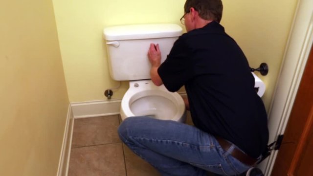 Plumber working on toilet seat