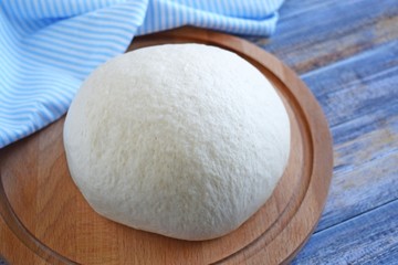 Dough for making delicious cinnamon buns on wooden background.